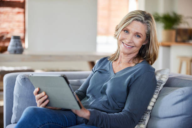 istock Mature woman using a digital tablet on her sofa and smiling 2007885774