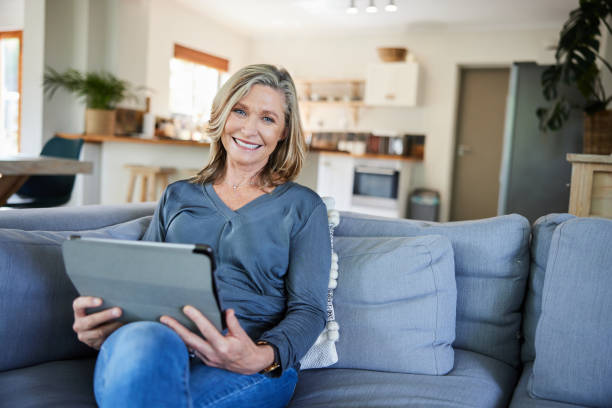 istock Smiling mature woman sitting on her sofa and using a tablet 2007886724