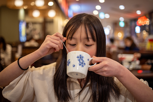 Teenage girl drinking a cup of tea after lunch in restaurant
