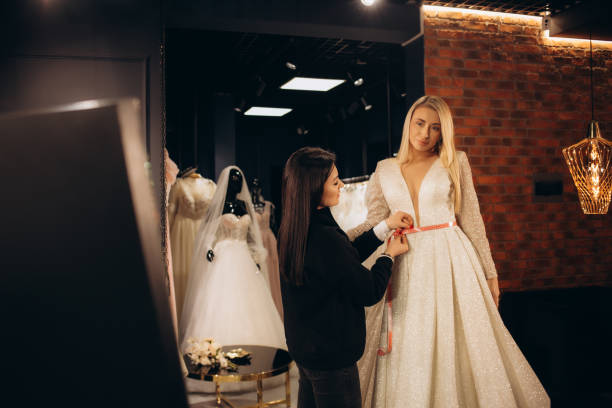istock Beautiful bride getting dressed by her best friend in her wedding day and choosing a wedding dress in the shop and the shop assistant is helping her 2007888297