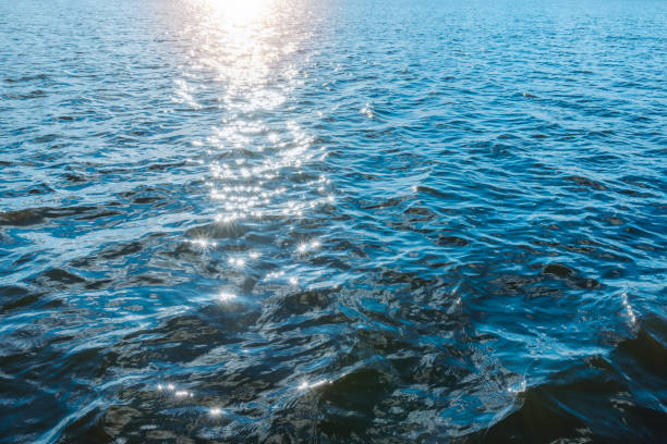 Wonderful natural blue water sun light reflects make sparkles in the sunset evening water.