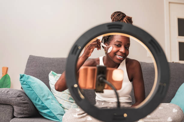 istock Happy African Woman Vlogging her Skincare Routine Using Jade Roller in front of ring light with smartphone at home 2007901519