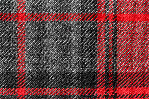 Red and black tartan fabric texture close-up. Traditional Scottish clothing and design. Background for your mockup