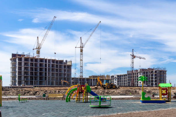 construction noise and vibration during multi-storey residential construction, landscaping and arrangement of children's playgrounds in a new microdistrict, selective focus