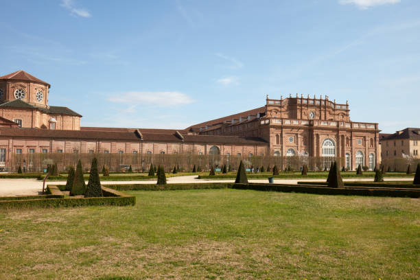 Venaria Reale, Italy - March 29 , 2023: Reggia di Venaria castle architecture and park with pyramidal hedges in spring sunlight