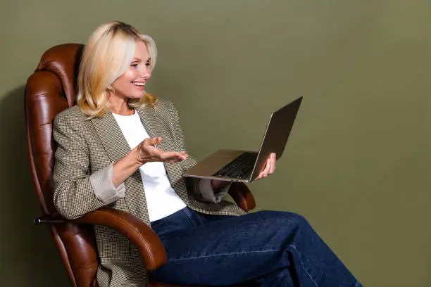 Photo of happy ceo manager woman holding light apple macbook having a conversation with colleagues isolated on khaki color background.