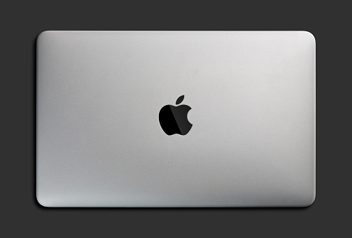 Top view of Macbook air notebook laptop computer with apple logo on topside. Macbook Pro 16 M1 chip laptop in grey, silver by Apple Inc. iMac on dark grey background isolated.