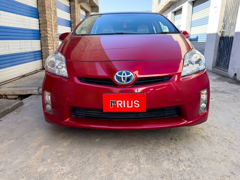 Red Toyota Prius car closeup view. Fuel-Efficient transportation concept: Swat, Pakistan - 08 Feb 2024.