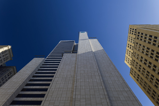 Skyscraper architectural details and structures in New York downtown, USA. Low angle view with lens flare and bright sun in the sky.