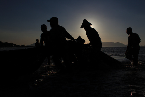 At dusk on 12/23/2019 , in the Javanese village of Banda Aceh, the silhouettes of Acehnese fishermen in their wooden boats were clearly visible as they spread nets (Pukat Darat) to catch fish. The golden sky accompanied their activity, creating a mesmerizing scene. Their diligence in seeking sustenance from the sea was reflected in their careful and skilled movements. A calm yet industrious atmosphere permeated the air, painting a beautiful picture of the traditional life still preserved along the shores of Aceh.