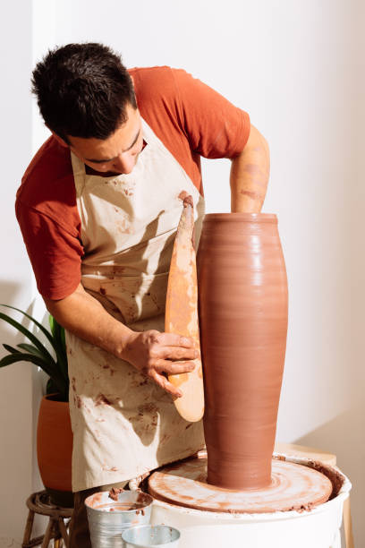 istock Male potter standing in studio creating clay vase 2008039610