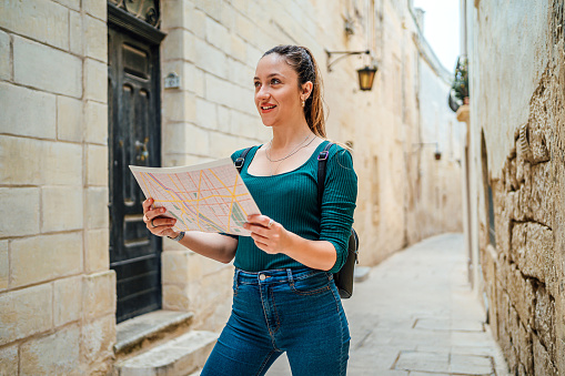 Cheerful female tourist using a map in Mdina, Malta