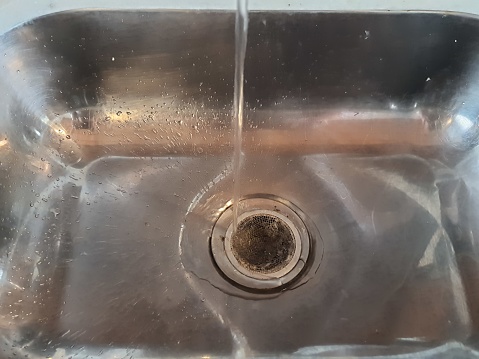 Close-up of water running in stainless steel sink.