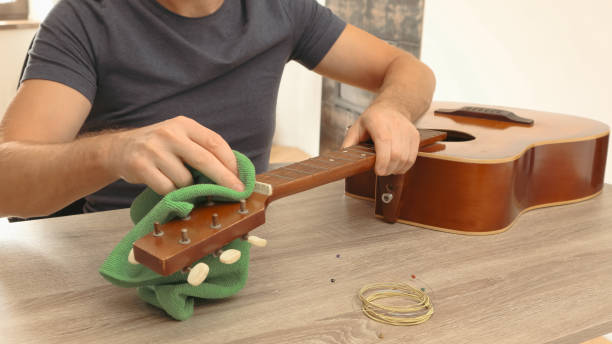 istock Man changing the strings of a guitar at home. Cleaning guitar. 2008057513