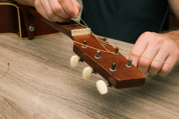 istock Hands of a young man changing the string on an acoustic guitar. Hand fixing guitar. 2008057523