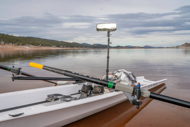 coastal rowing shell, literace 1x by liteboat, with a mirror and waterproof bag on a shore of carter lake in northern colorado in winter scenery. - 1x - fotografias e filmes do acervo