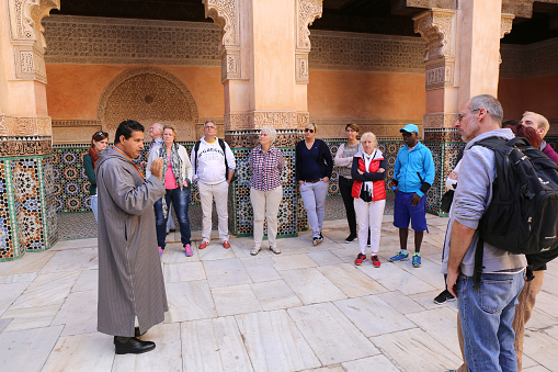 Marrakesh, Morocco-December 10,2015:Moroccan Tourist Guide giving information about palace to German Tourists