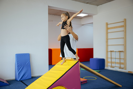 Cute active child girl in sensory integration room, kindergarten. Kid is active leisure. Childhood and sporty lifestyle.Sports weekend in gymnastic center. Fitness,healthy, develop skills concept