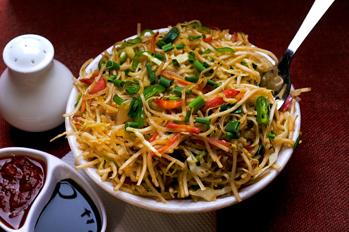 Schezwan Noodles or vegetable Hakka Noodles, or chow mein is a popular Indo-Chinese recipes, served in a bowl, Stir-fried noodles.