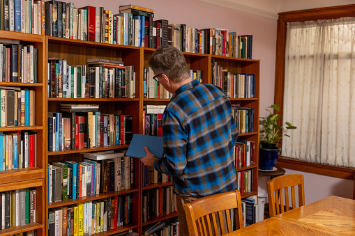 Inside the home of a mature man using and enjoying his home library in an authentic Victorian home.