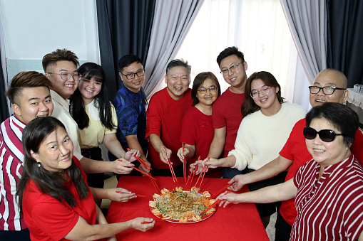 Family members enjoying 'YuSheng' (Yee Sang or Prosperity Toss) at home