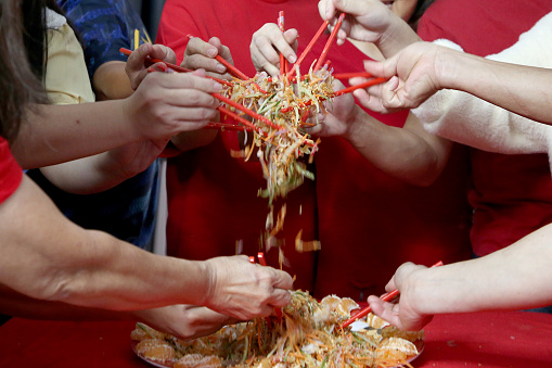 Family members enjoying 'YuSheng' (Yee Sang or Prosperity Toss) at home