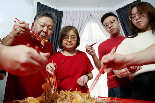 Family members enjoying 'YuSheng' (Yee Sang or Prosperity Toss) at home