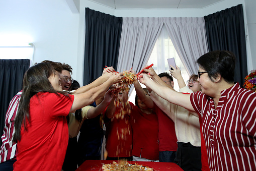 Family members enjoying 'YuSheng' (Yee Sang or Prosperity Toss) at home