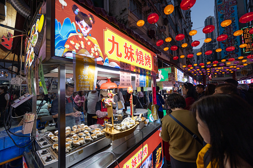 Hong Kong - February 13, 2024 : People visit food stalls at Temple Street Night Market in Hong Kong.