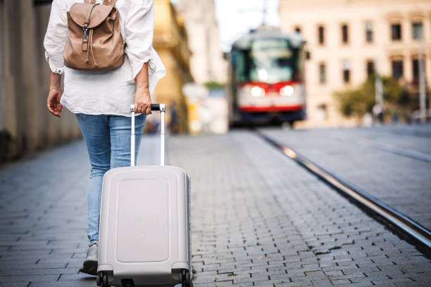 istock Woman tourist with backpack pulling suitcase and walking on city street 2008201012