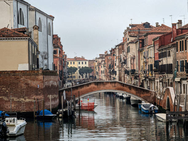 Venice, Italy – December 29, 2023: Boats gently float beneath a canal bridge in Venice, Italy