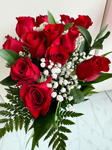 Delicate wedding bouquet of beige and red roses on a white leather armchair