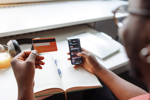 Young man holding a credit card and a smart phone. He is doing some online shopping