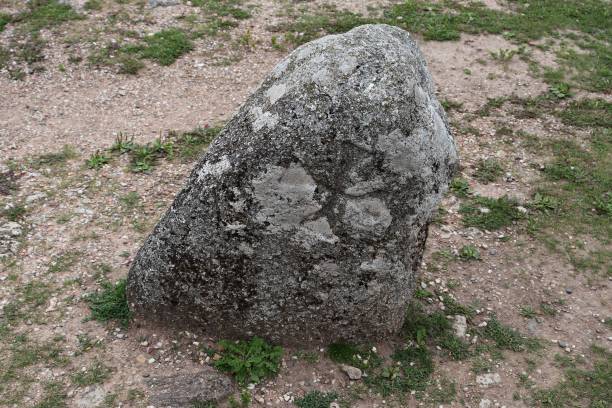 istock An old gray stone with a Maltese cross, dug into the ground, left over from distant ancestors 2008314820