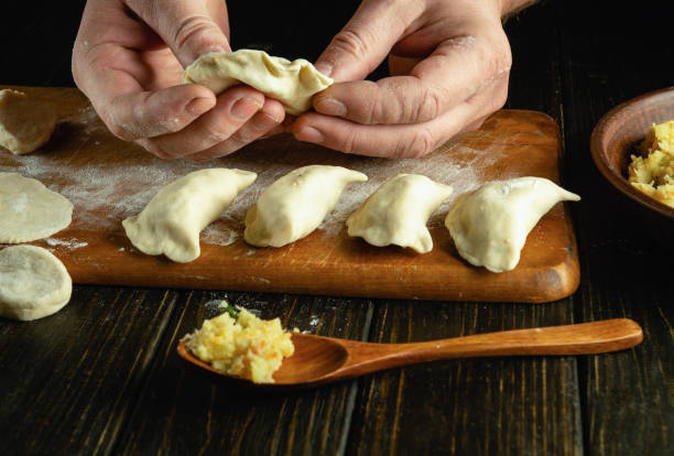 istock Chef hands close-up making dumplings from dough. The concept of cooking dumplings with potatoes on the kitchen table in a restaurant 2008319599