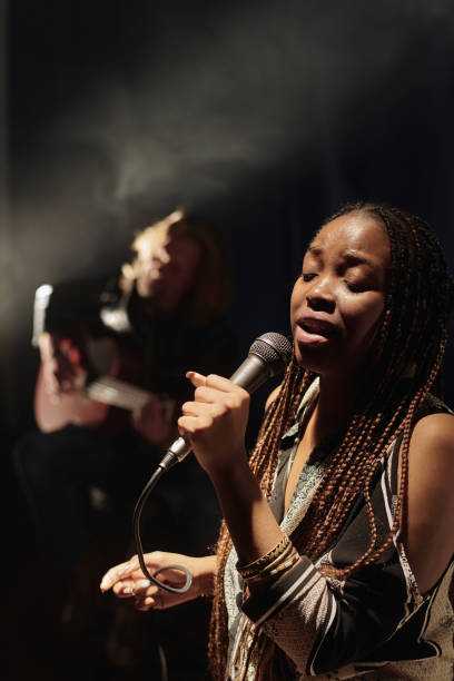istock Black Female Musician Singing into Microphone on Stage with Band 2008322341