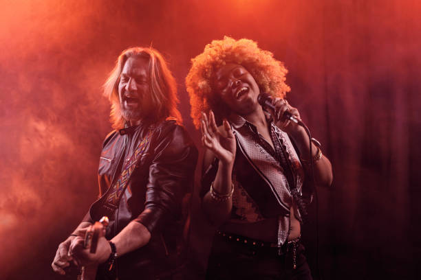 Female singer with microphone and rock and roll band performing hard rock music on stage