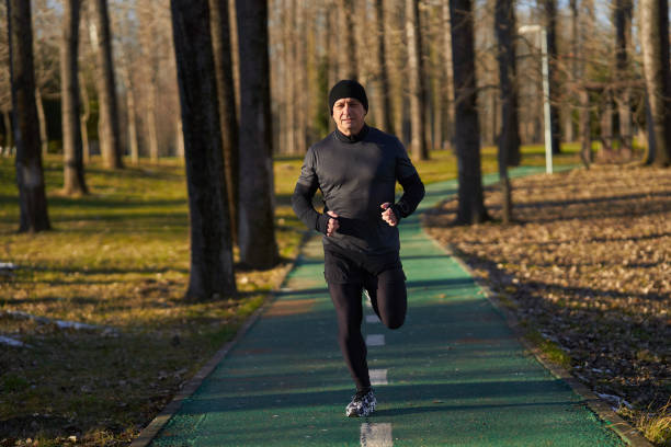 Mature athlete running in the park in a cold sunny winter day
