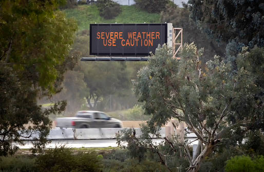 Digital road sign stating Severe Weather Use Caution with a truck passing under it. The shot is on the 15 freeway in Escondido California