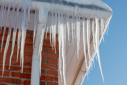 Close-up of shiny icicles on a roof gutter on a sunny day.