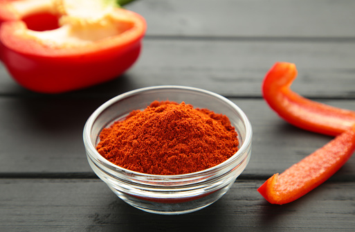 Paprika powder with fresh red pepper on blue background. Top view