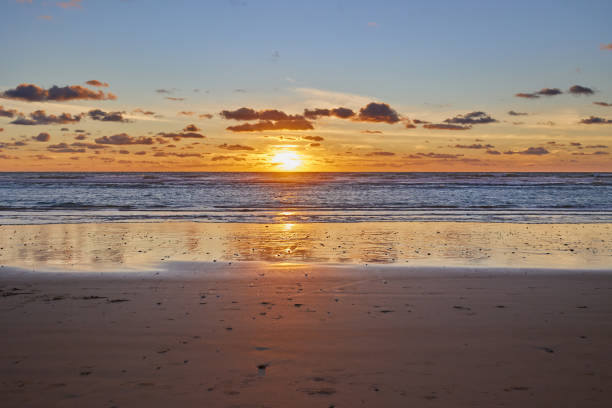 Dramatic sea sunset. The setting sun sinks into the sea. Calm waves roll onto the sandy beach.