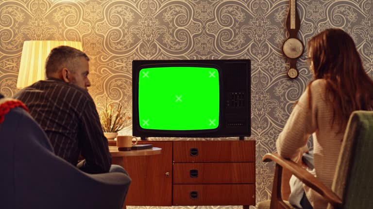 DS An old TV set with a green screen and couple sitting in the living room and talking