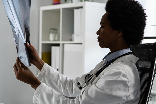 Female doctor  examining a patient's X-ray at her office