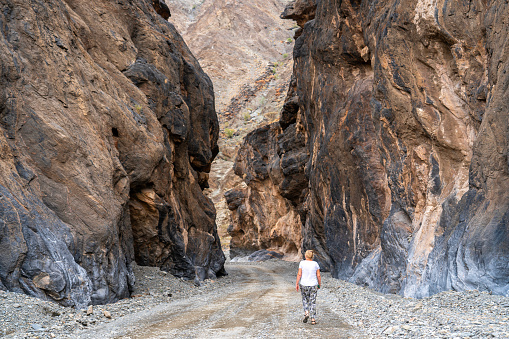 Woman rear view walking on spectacular road through Wadi Bani Awf—one of Oman’s most picturesque valley.