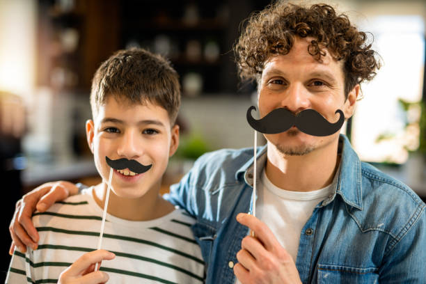 istock Dad and son holding fake mustache. 2008428376