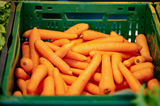 Pile of baby carrots sitting in green bin next to each other.