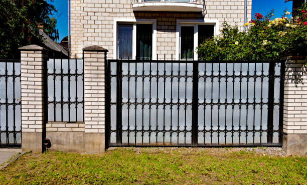istock Black wrought iron fence in front of brick building with windows. 2008483794
