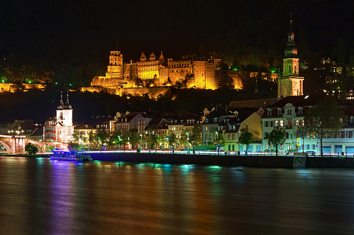 Heidelberg, Germany - September 29, 2013: Heidelberg Castle, tower of Church of the Holy Spirit, and fragment of Karl Theodor Bridge with bridge gate in night. View from the opposite bank of Neckar river. The castle ruins are among the most important Renaissance structures north of the Alps.