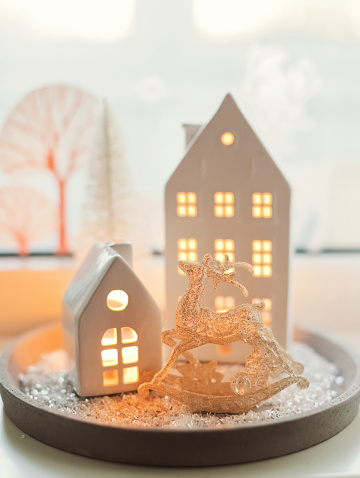 White ceramic house decoration with candles on a grey tray